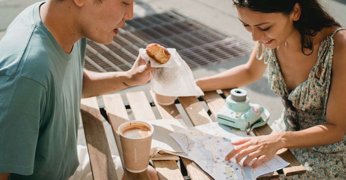 Visualizing Instagram Travel photo locations on a Map - Diverse couple having breakfast in cafe while exploring map