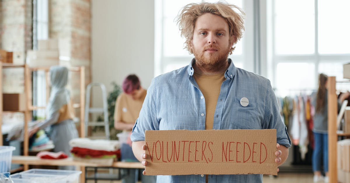 Volunteer in UK – which visa needed? - A Man Holding a Cardboard with Inscription