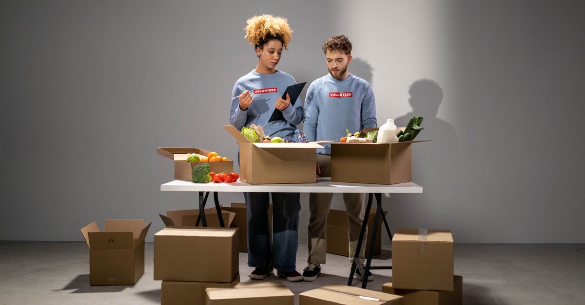 Volunteering work - Man and Woman Standing near Brown Cardboard Boxes