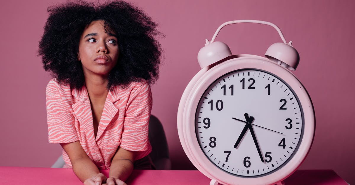 Waiting time when applying for a German passport abroad? - Woman in Pink Long Sleeve Shirt Sitting Beside White and Pink Alarm Clock