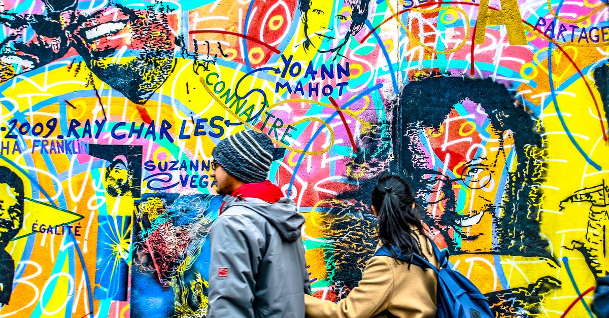 Walking experience in Berlin - Man and Woman Walking Beside a Wall with Graffiti