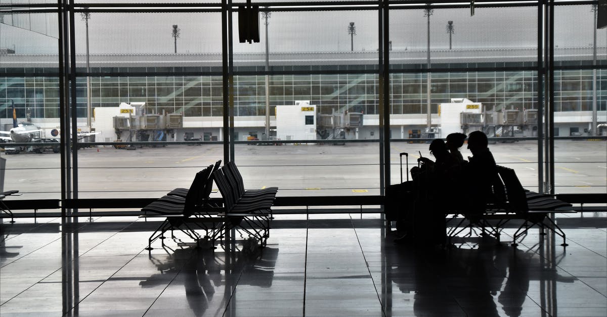 Want to meet arriving passenger inside airport before immigration (SIN airport) - Silhouette of unrecognizable passengers sitting on chairs with luggage near  window and waiting for flight