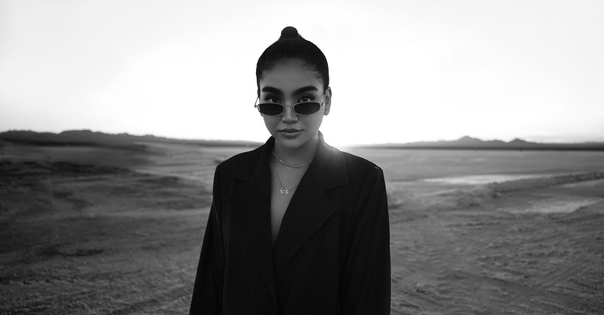 Wearing neoprene suit in airplane? - Black and White Portrait of Woman Wearing Sunglasses and Suit Standing in Empty Field