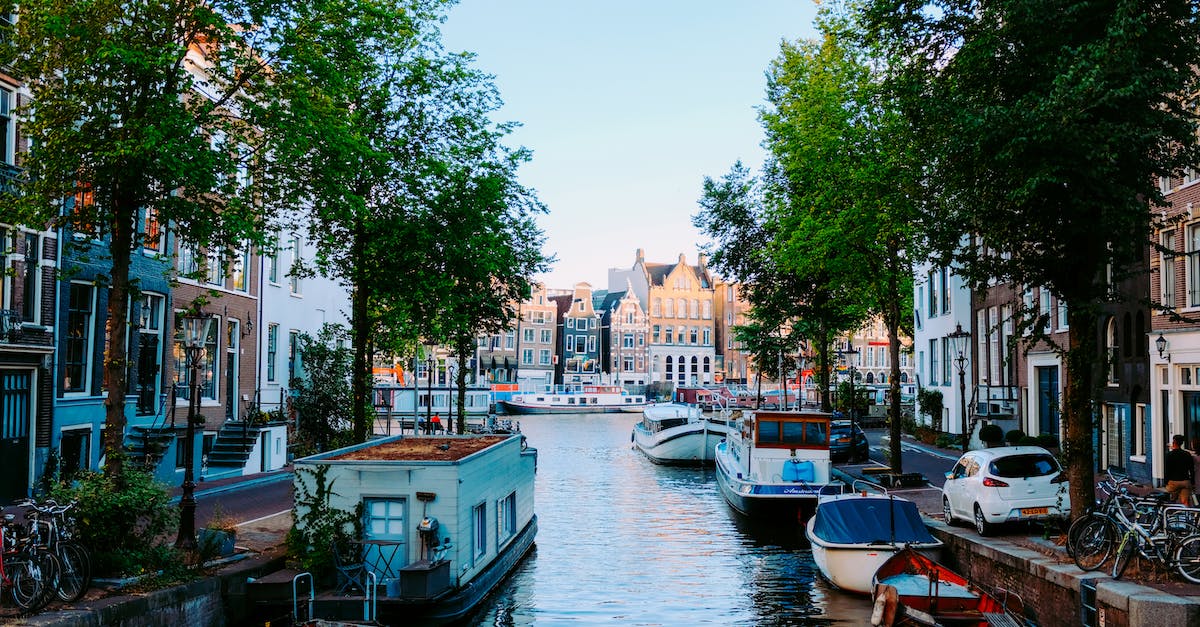 What's a cheap ski location to reach from Amsterdam (Netherlands)? [closed] - Peaceful scenery of Amsterdam streets with typical houses against channel with moored boats on clear sunny day