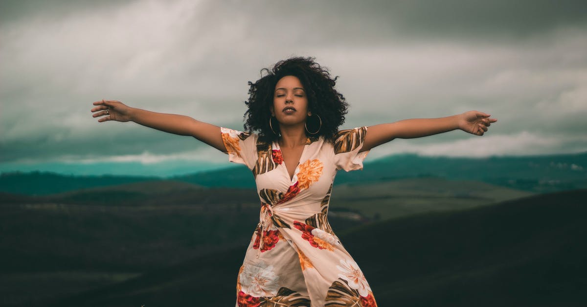 What's my travel style? [closed] - Woman in White and Red Floral Dress Standing on Green Grass Field