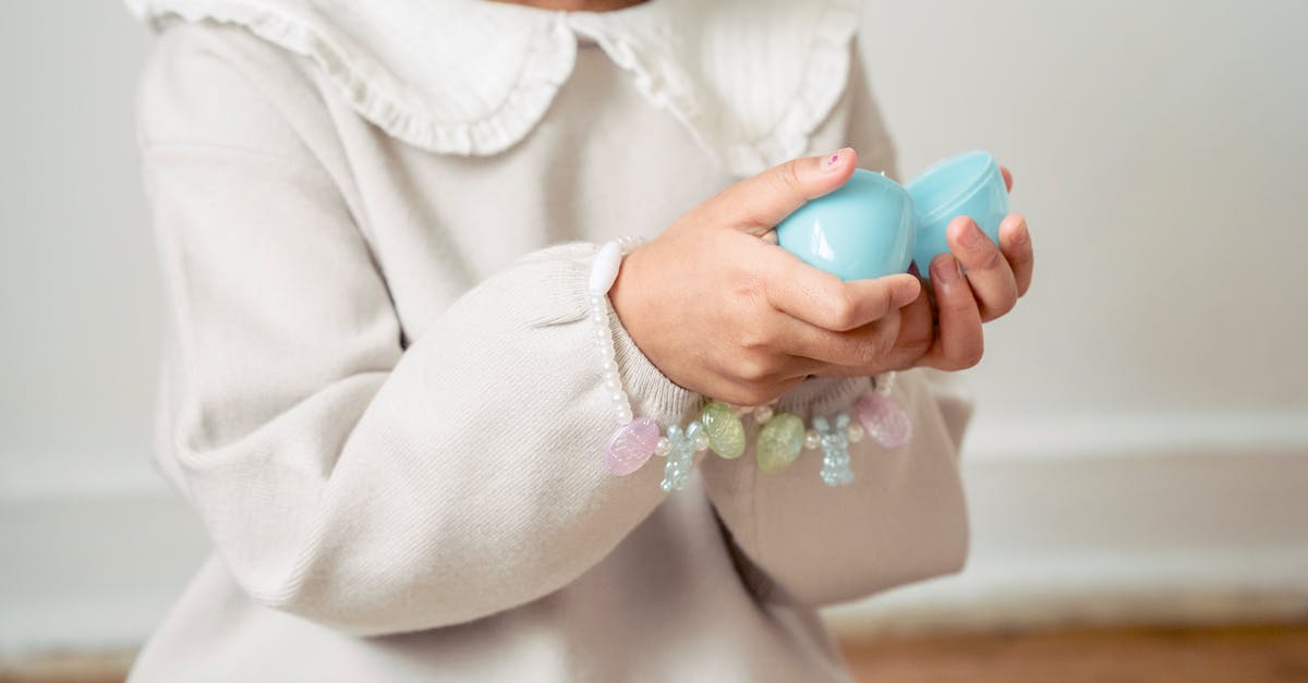 What's open over Easter in Germany? - Crop unrecognizable girl in white dress opening surprise toy egg in light room