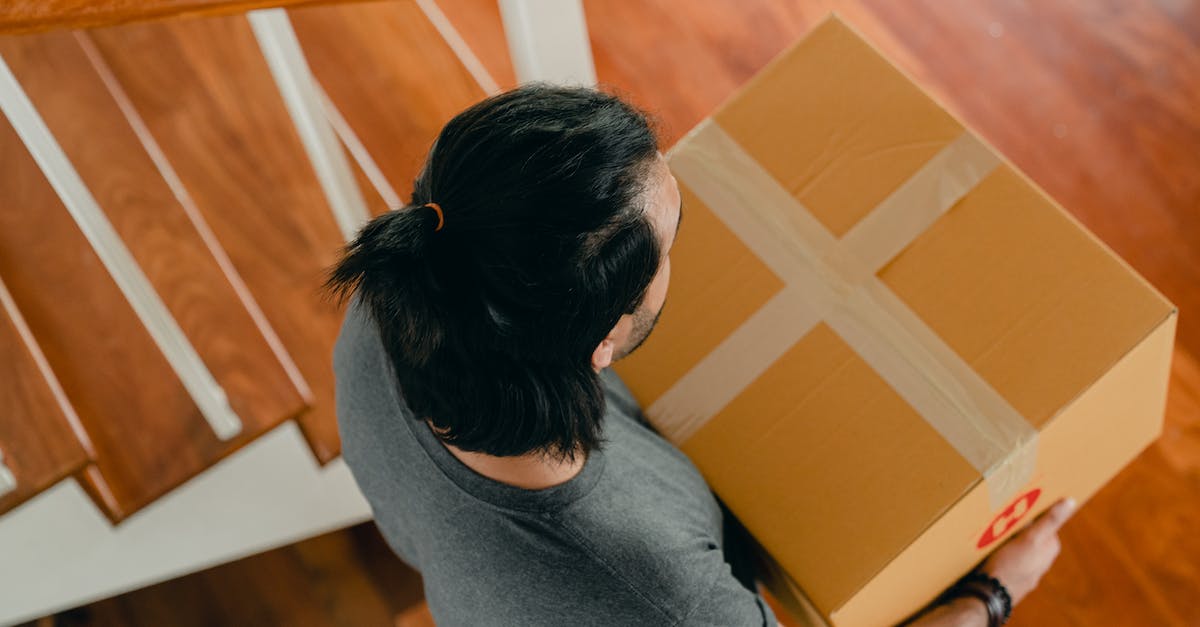 What's the cheapest method to send a large package from New Zealand? - Man carrying box in new apartment