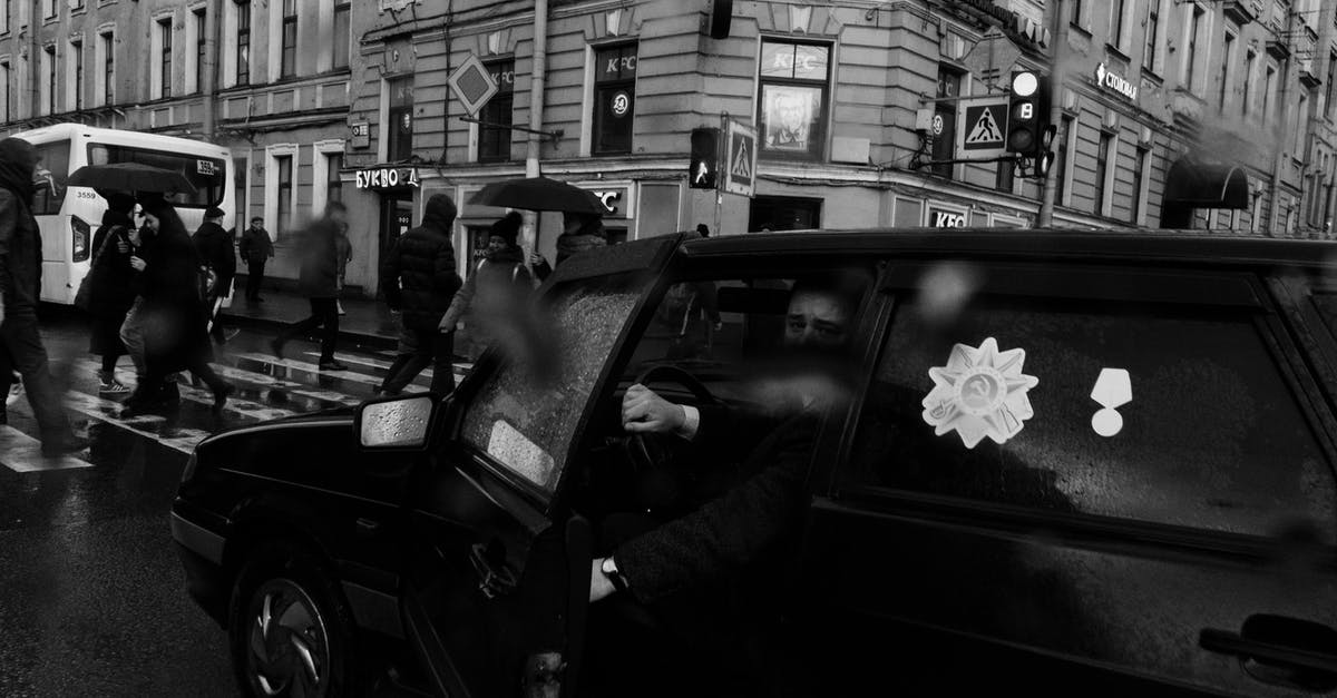 What's the cheapest way to stay in Copenhagen? [closed] - Man in black car with medal stickers stopped near crosswalk