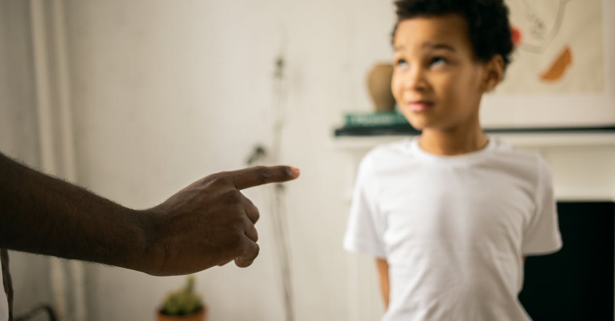 What's the point of hand-filled immigration forms? - Upset little ethic boy looking at faceless father during argument