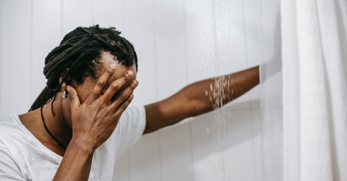 What's the use for this shower drain cover? - Sad African American man covering face with hand in shower cabin
