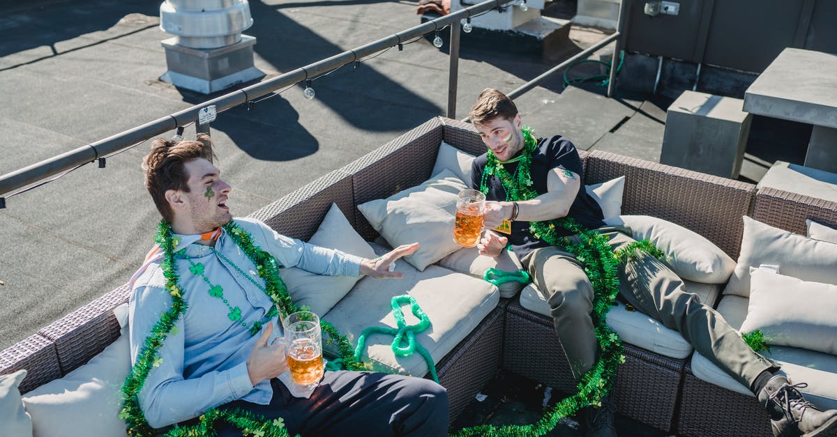 What airlines offer complimentary alcohol from Ireland to the U.S.? - From above of Irish friends sitting on sofa with beer while celebrating holiday on terrace and looking at each other