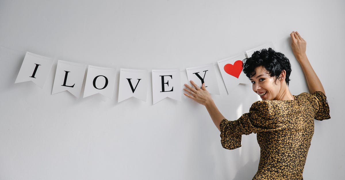 What am I supposed to present in my Schengen visa application? - Cheerful female female looking at camera while hanging garland with white flags with romantic inscription on wall during Saint Valentines day