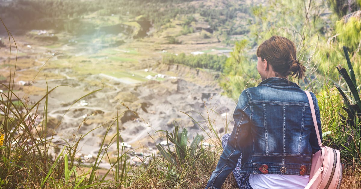 What are some easy / moderate day hikes in the Maloti-Drakensberg Park? - Woman Wearing Blue Denim Jacket Sitting on Cliff Overlooking Open Field