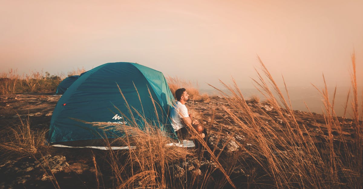 What are some strategies for keeping solo travel costs down? - Photo of a Man Sitting Outside the Tent