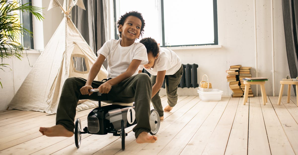 What are the benefits to scheduling an Uber Ride ahead of time? - Happy barefoot African American brothers in casual wear riding toy car while playing together in light room with blanket fort