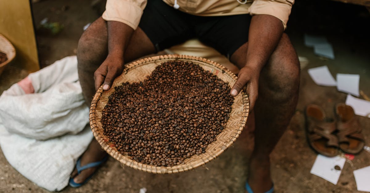 What are the places that sell coffee beans called in Turkey? - Crop ethnic person with coffee beans on plate