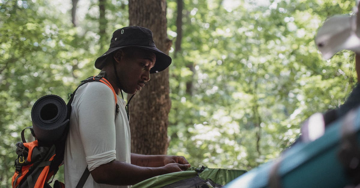 What are the recommended concentration camp tours near Berlin? - Concentrating young black guy setting up camping tent in woods