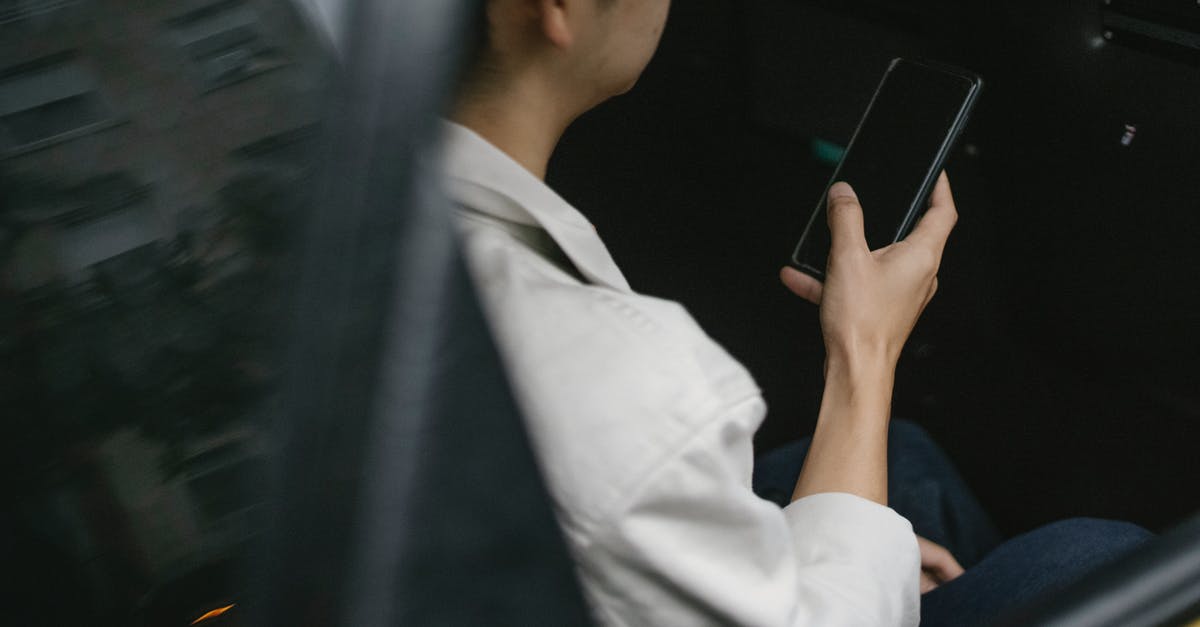 What are the taxi options from Prague Airport? - High angle of taxi passenger using smartphone while sitting on backseat