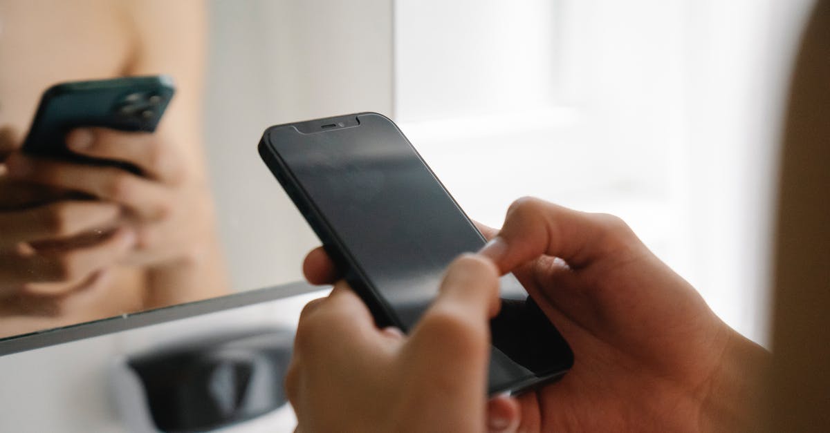 What can border guards check on your smart phone when entering USA? - Crop unrecognizable person standing and using modern smartphone in light room in daytime