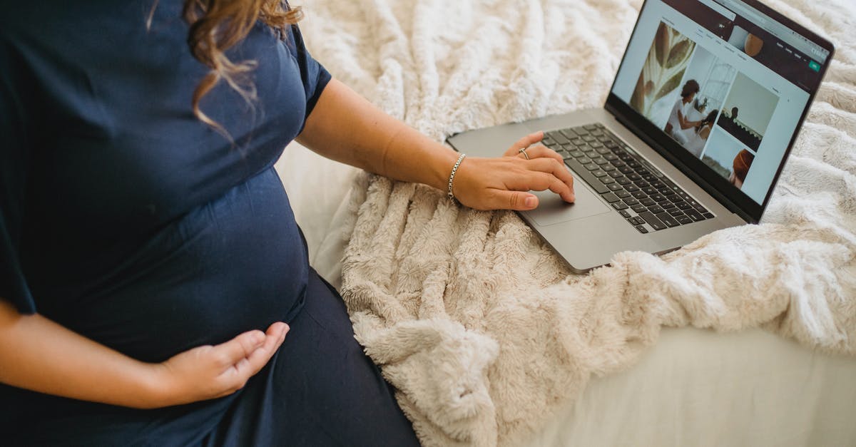 What can I expect when bringing in my netbook to China? - From above of crop anonymous expectant female caressing belly while surfing internet on netbook on cozy bed