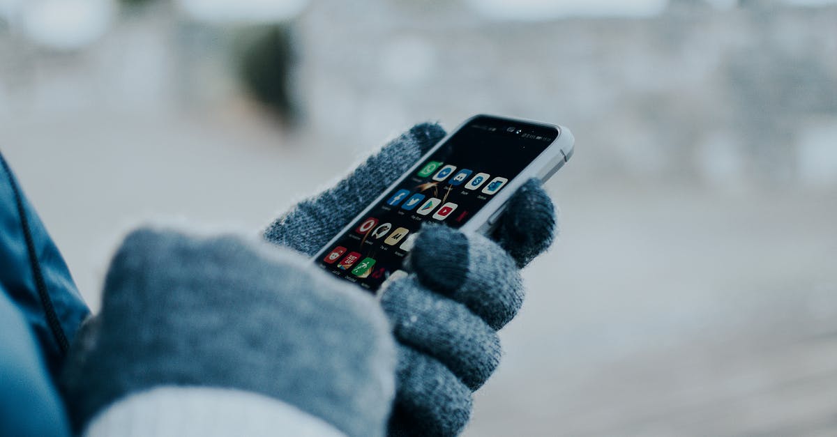 What cell provider should I use in Dubai? [closed] - Person Wearing Gloves Holding a Cellphone