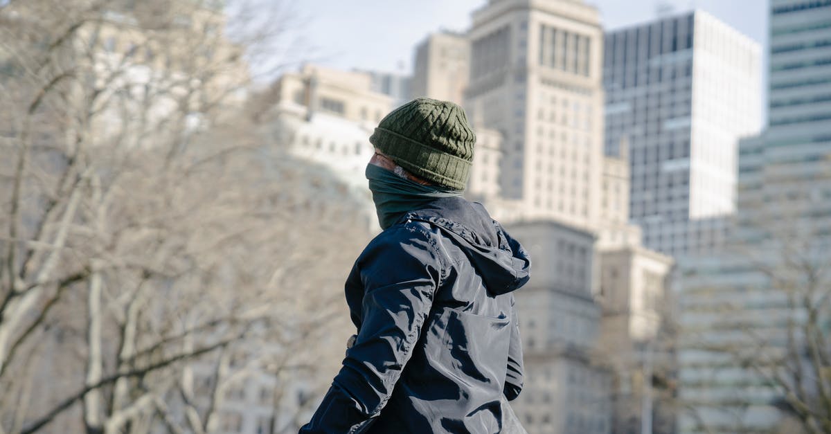 What city are these buildings in? - Person in Black Jacket and Green Knit Cap in the Park