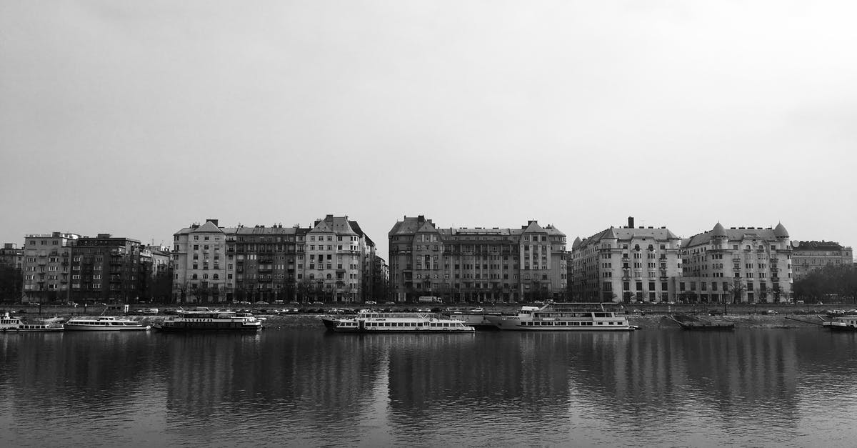 What city are these buildings in? - Grayscale Photo of City Buildings Near Ships on a River