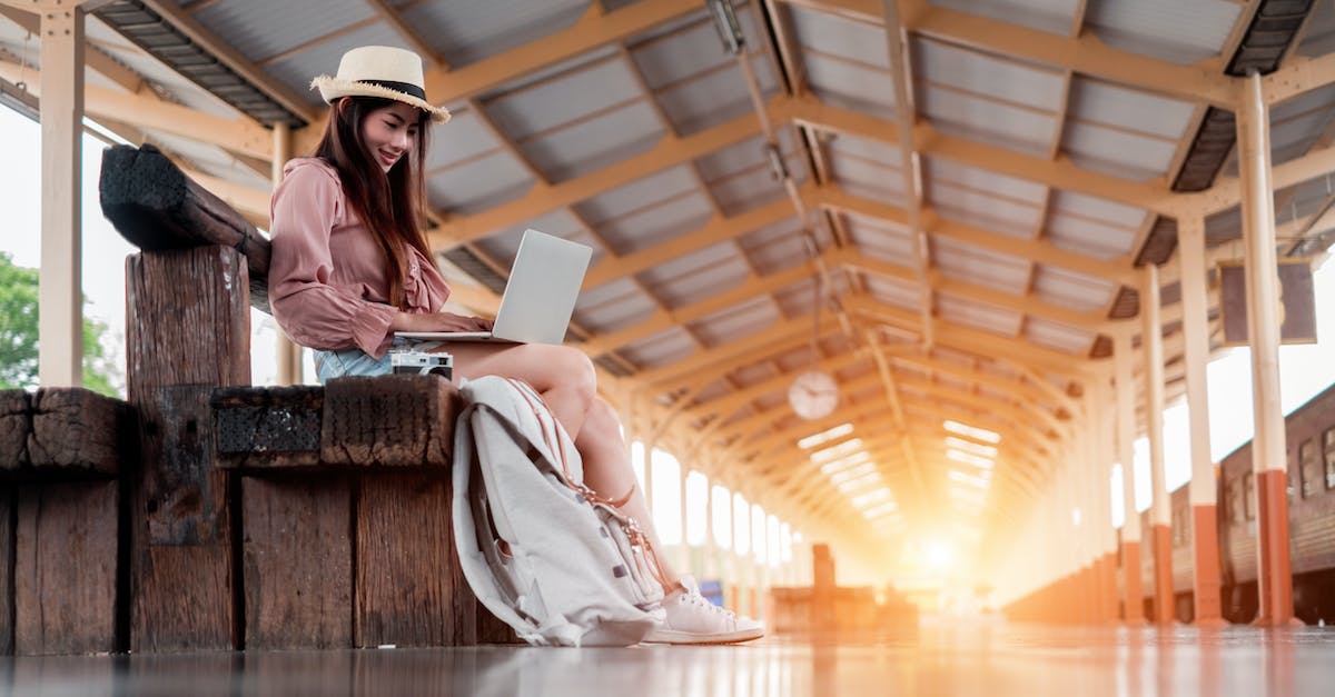 What class of travel is suitable for a woman travelling alone on Indian railways? - Low Angle Photo of Smiling Woman Using A Laptop Sitting on Wooden Bench at Train Station Platform