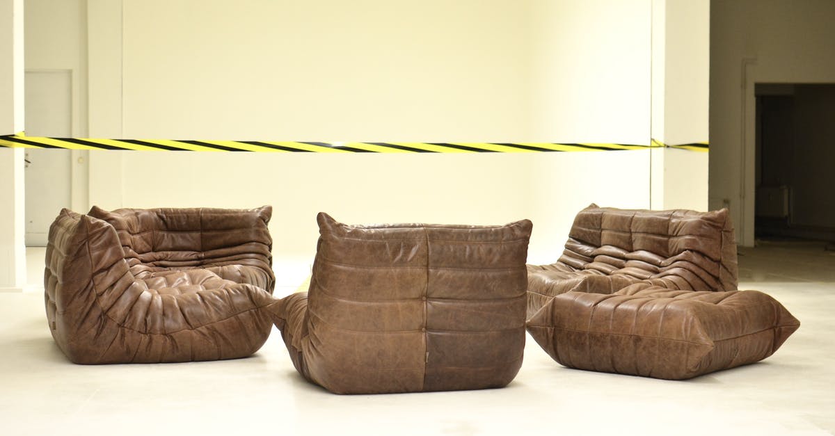 What countries restrict liquids being carried through security at airports? - Leather couches placed in empty room under bright striped barrier tape during renovation process