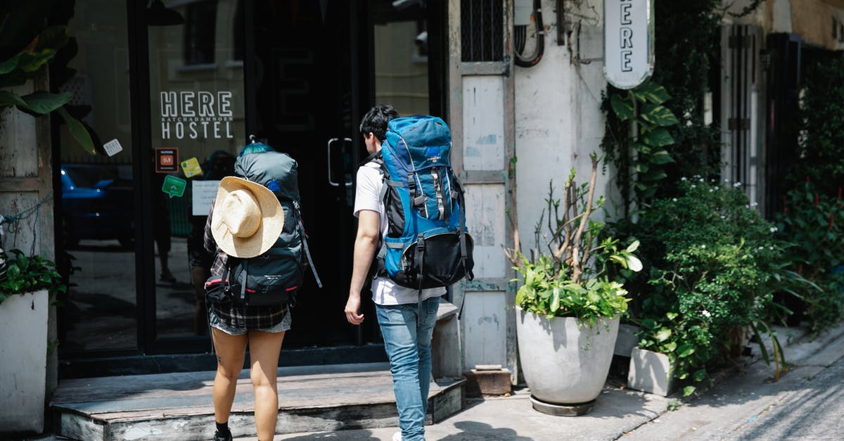 What dates to enter when purchasing travel insurance? - Unrecognizable couple of travellers with backpacks entering hotel