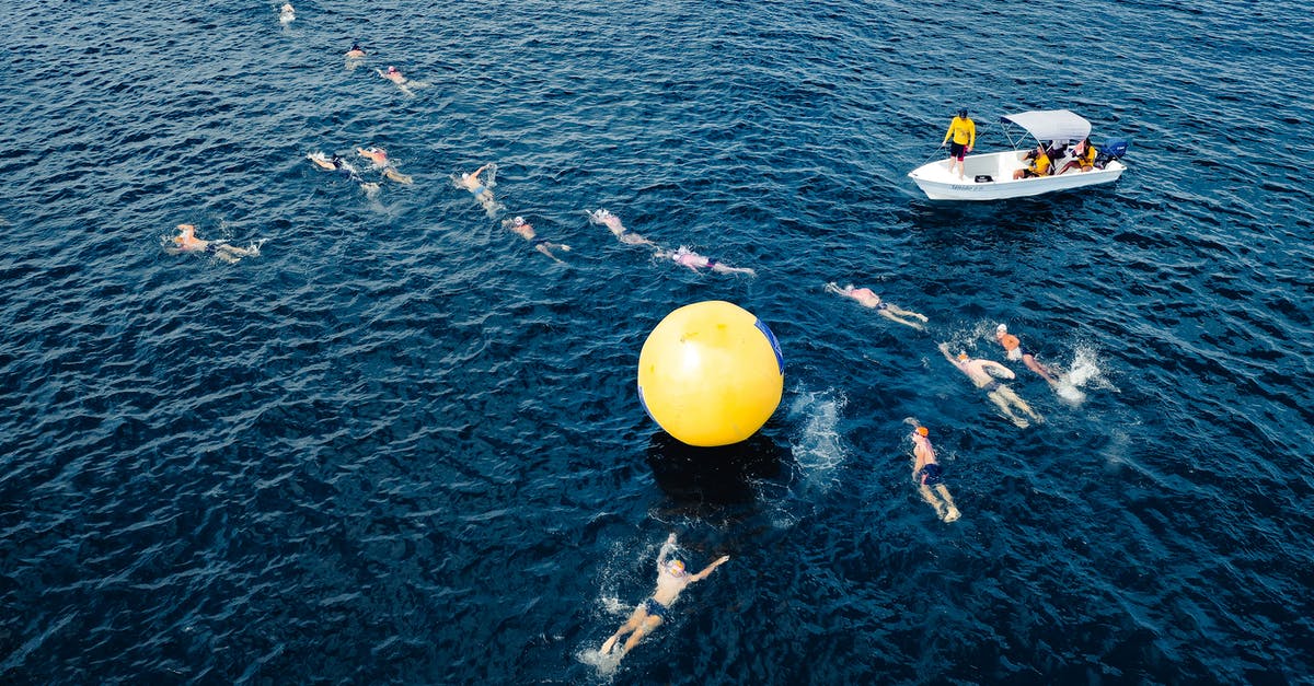 What dates to enter when purchasing travel insurance? - Aerial view of swimmers taking park in race and swimming around big yellow inflated ball in sea water