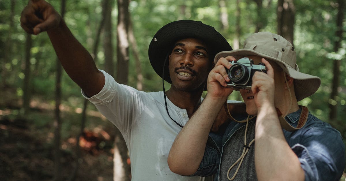 What dialect of Spanish do the locals speak in Panama City? - Young black male traveler indicating with finger near anonymous best friend taking photo on camera in woods