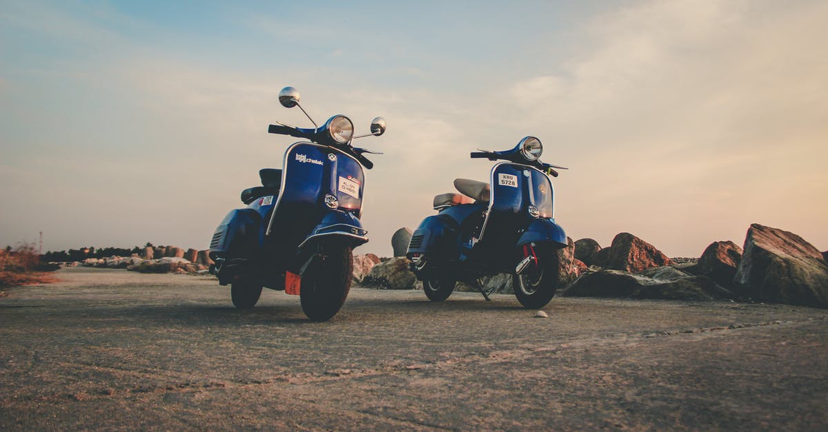 What documents are required to drive a motorcycle from Kazakhstan to China? - Blue mopeds parked on empty road in countryside