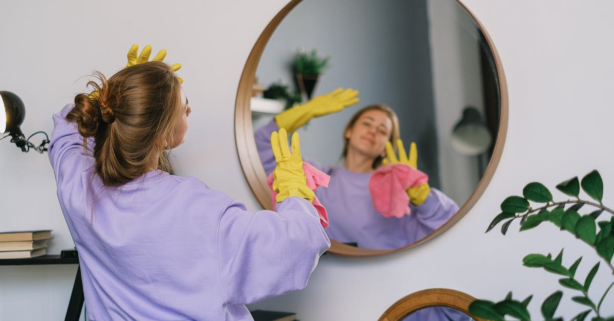 What does the TSA consider to be household cleaners? - Back view of young female in casual clothes and latex gloves standing against mirror and dancing while cleaning light room in daytime