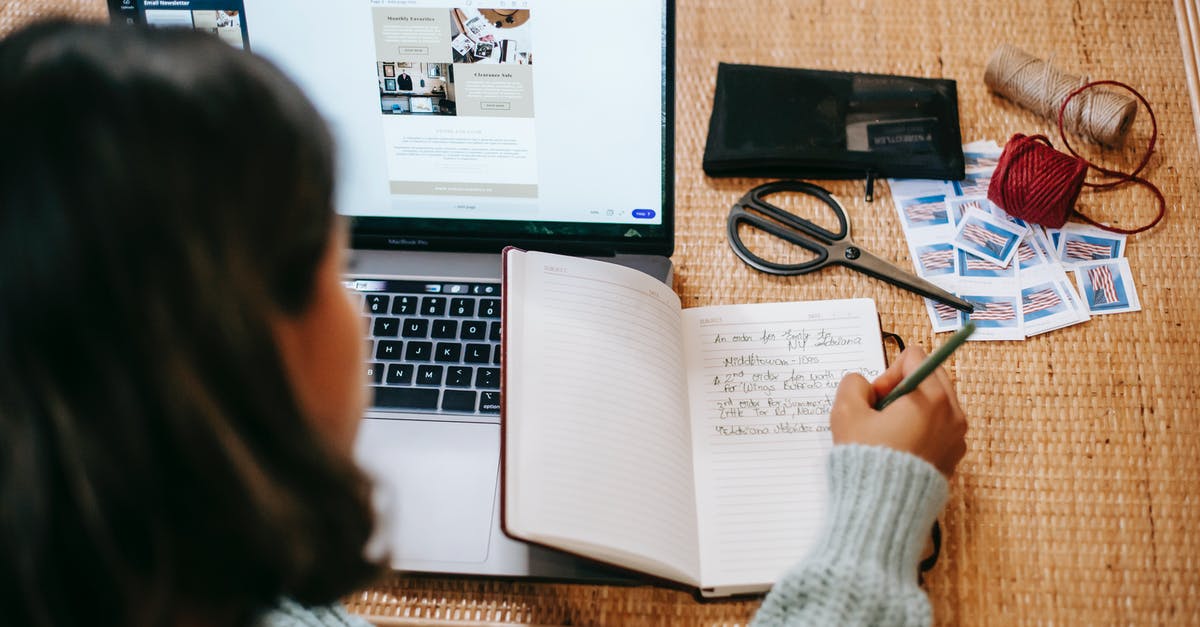 What does this pen notation in my UK entry stamp mean? - High angle of anonymous ethnic woman in casual clothes writing information in notepad at table near netbook and scissors near stamps and balls of thread in bright apartment