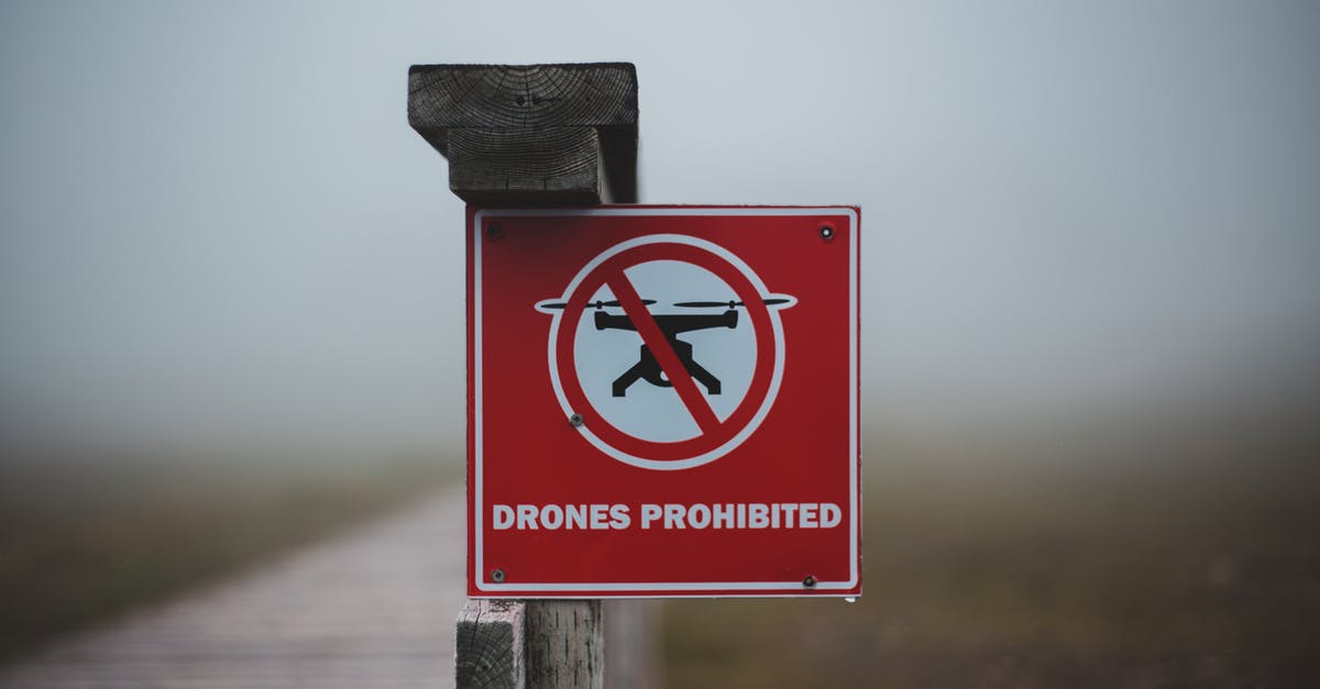 What does this sign on Air Tahiti ferry mean? - Sign prohibiting use of drones placed on wooden fence near wooden walkway in field in foggy day