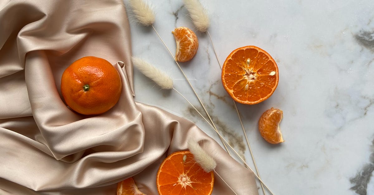 What dried food can I take across the American border from Canada? - Top view of fresh ripe slices of tangerine and oranges placed on crumpled fabric on marble surface with dried branches