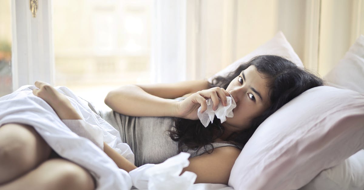 What happens if you become seriously ill during a flight? - Woman Lying on Bed While Using Tissue