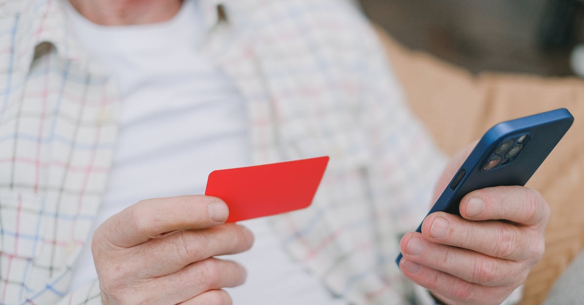 What happens if you cannot pay for a hotel? - A Person's Hands Holding a Card and a Cell Phone