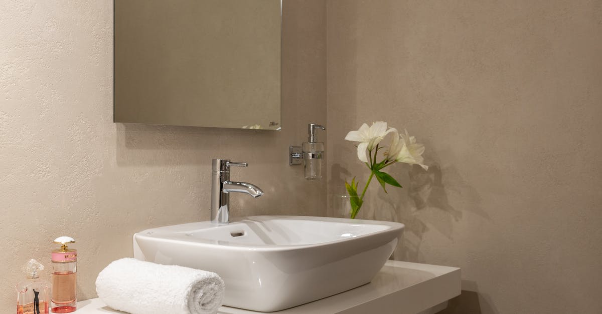 What happens to the unfinished open soaps in hotel bathrooms? - Interior of bathroom with white wrapped towel near ceramic basin and faucet with mirror on wall