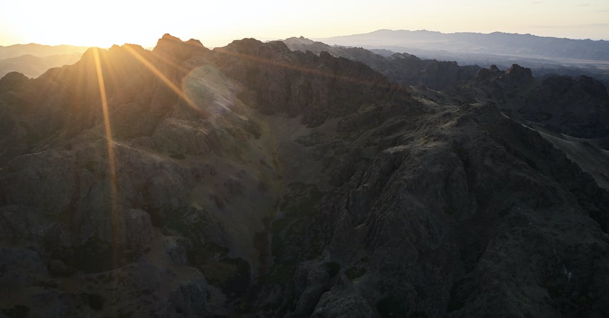 What happens to visas that last longer than a passport? - Majestic drone view of mountain range almost plunged into darkness touched by last sunbeam of setting sun causing lens flare