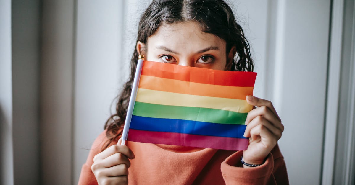 What identification is acceptable to show in Portugal? - Young ethnic anonymous female demonstrating bright LGBT flag and looking at camera on blurred background