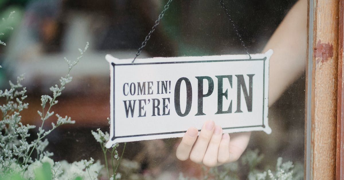 What information does UK Immigration store on EEA entrants? - Crop anonymous person flipping signboard on window of floral shop in modern city