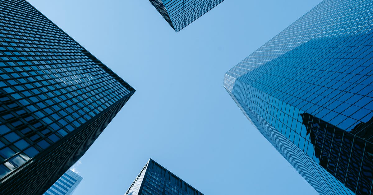 What is a business center in a hotel? - Low angle of high business towers with glass mirrored windows located in megalopolis downtown against blue sky