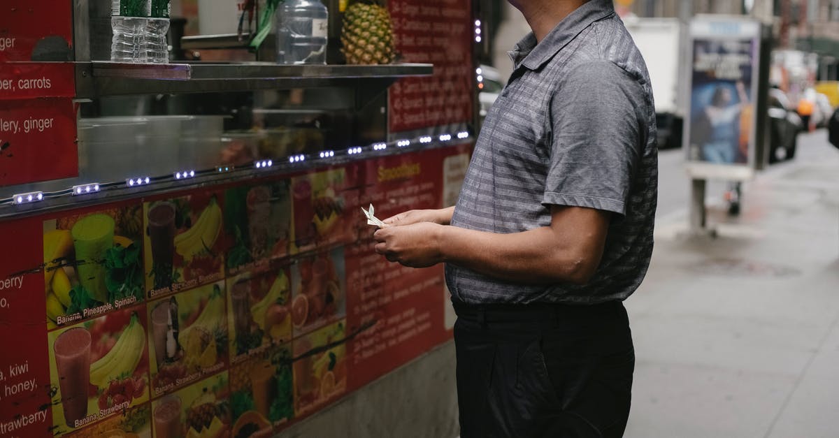 What is included in the VFS $75 walk in service? - Side view of tranquil man with banknotes buying street food at food truck with fruits on street in town