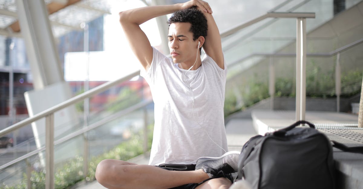 What is non-personal luggage in the eyes of EU customs? - Young ethnic athlete in earbuds stretching body while sitting on stairs at entrance of contemporary building