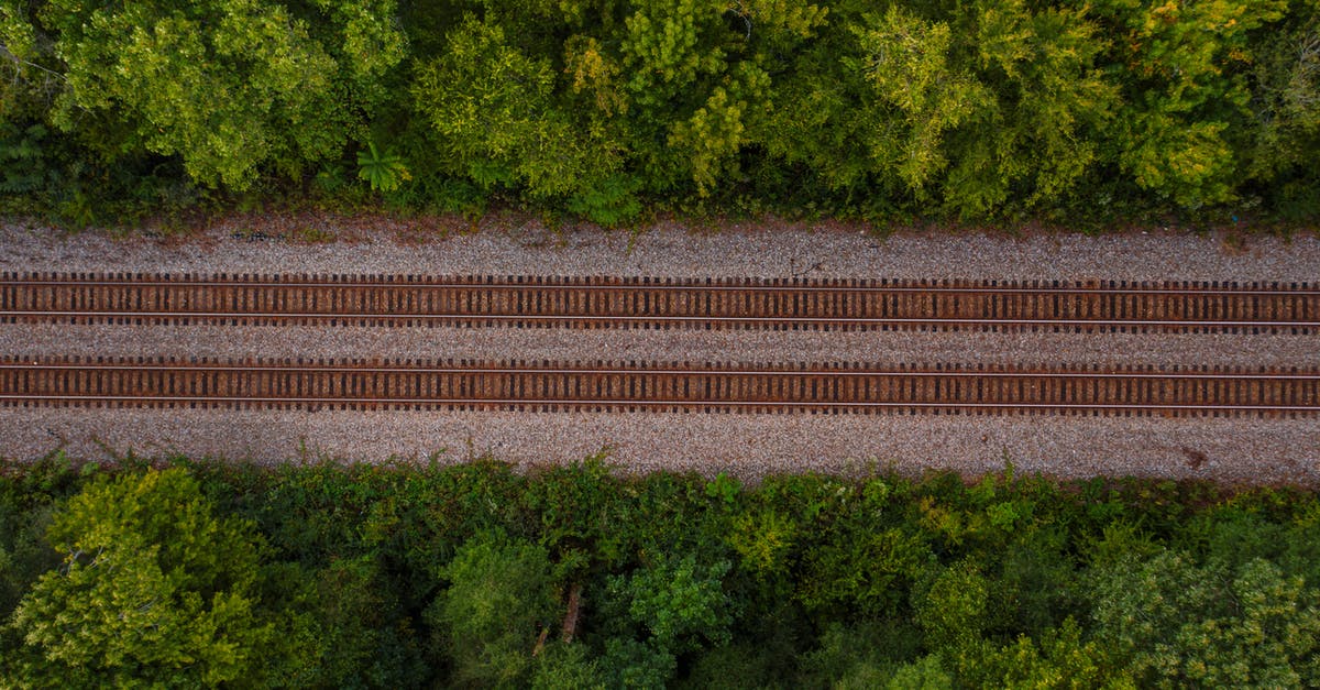 What is the best value way to travel by rail from Southend airport to ExCel in London and then to Gatwick? - Drone view of empty straight railway tracks running between lush green trees on sunny day
