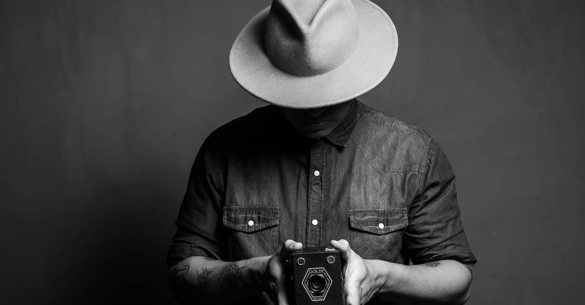 What is the best way to carry photographic film when travelling? - Man in hat showing retro camera