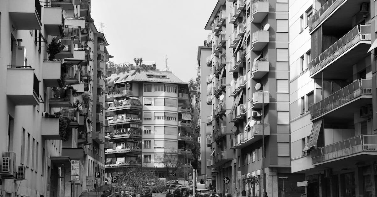 What is the best way to get from Rome to Venice? - Black and white of residential district of Rome with typical buildings and various cars parked on narrow asphalt road