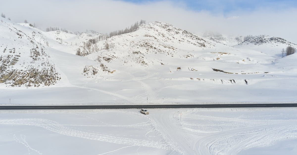 What is the cheapest way to see snow from Singapore? - Modern car riding along road against snowy hills